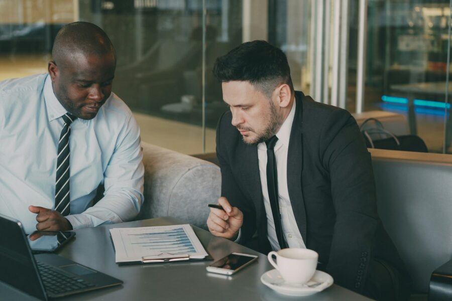 Two businessmen reviewing financial charts and a development plan at a table