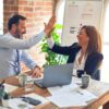 Franchise Broker Network Playbook: How Franchisors Recruit, Train, and Cut Brokers Without Channel Chaos 5 Franchise development partners celebrating a successful meeting with a high five across an office desk